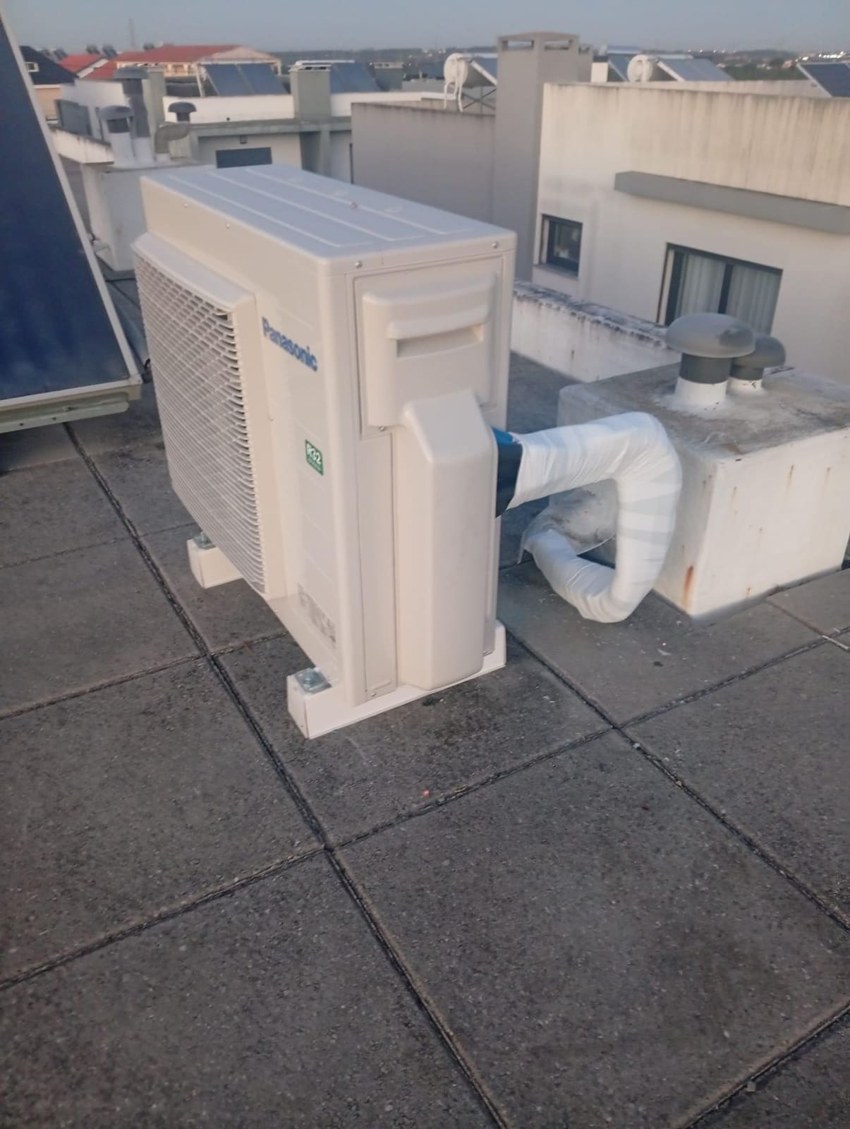 Unidade exterior de ar condicionado com tubagem num terraço